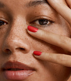Close-up of a woman with Pink Gellac 163 Rockstar Red manicured nails near her face.