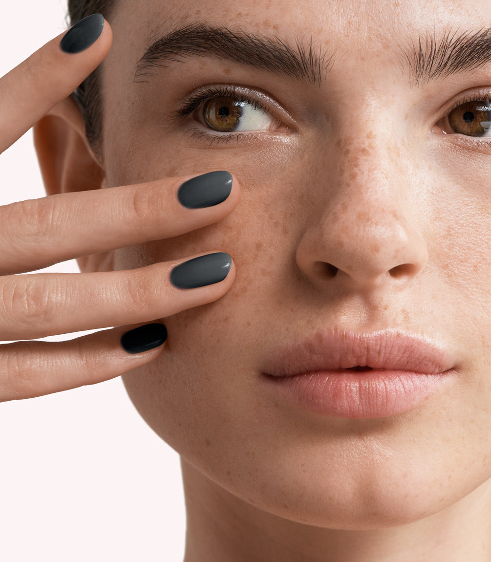 Close-up of a woman with Pink Gellac 169 Smoked Grey manicured nails near her face.