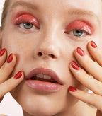 Close-up of a woman with Pink Gellac 178 Ultimate Red manicured nails near her face.