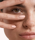 Close-up of a woman with Pink Gellac 194 Ivory Blush manicured nails near her face.