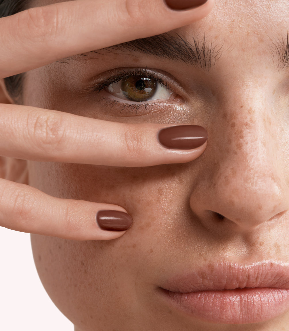 Close-up of a woman with Pink Gellac 203 Chocolate Brown manicured nails near her face.