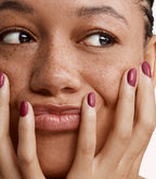 Close-up of a woman with Pink Gellac 205 Burgundy Red manicured nails near her face.