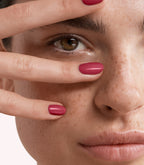 Close-up of a woman with Pink Gellac 229 Berry Red manicured nails near her face.