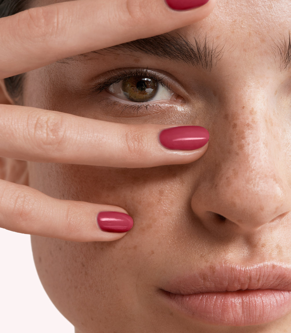 Close-up of a woman with Pink Gellac 229 Berry Red manicured nails near her face.