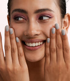 Close-up of a woman with Pink Gellac 231 Strictly Silver manicured nails near her face.