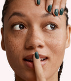 Close-up of a woman with Pink Gellac 232 Chemistry Green manicured nails near her face.