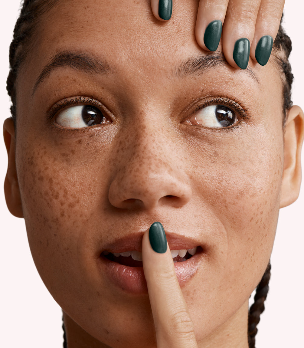Close-up of a woman with Pink Gellac 232 Chemistry Green manicured nails near her face.