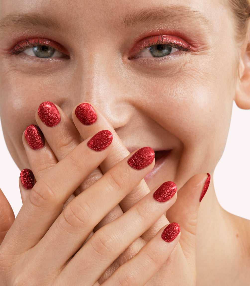 Close-up of a woman with Pink Gellac 233 Flashy Red manicured nails near her face.