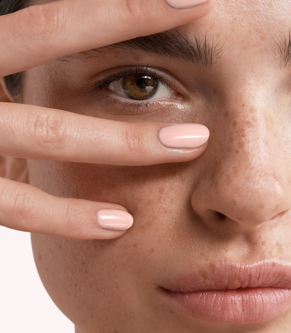Close-up of a woman with Pink Gellac 238 Peachy Nude manicured nails near her face.