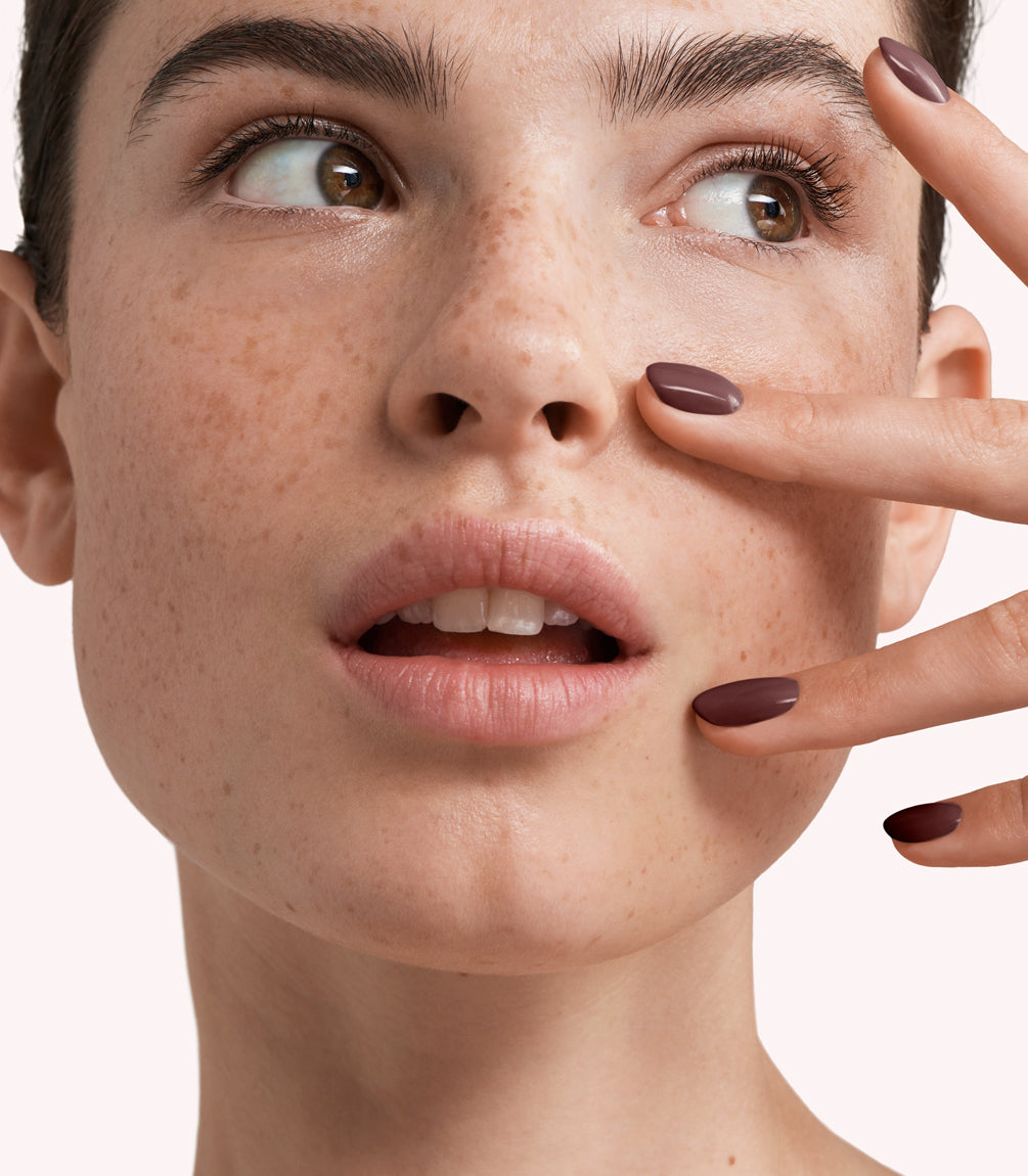 Close-up of a woman with Pink Gellac 257 Burnt Taupe manicured nails near her face.