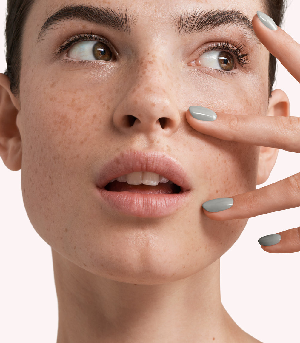 Close-up of a woman with Pink Gellac 264 Lady Grey manicured nails near her face.