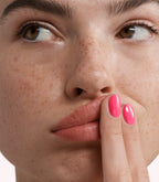 Close-up of a woman with Pink Gellac 270 Florida Pink manicured nails near her face.