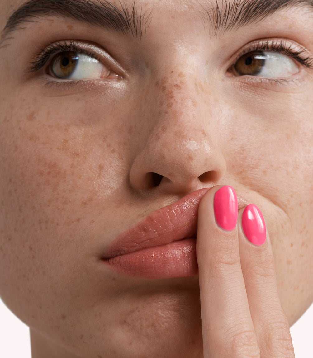 Close-up of a woman with Pink Gellac 270 Florida Pink manicured nails near her face.