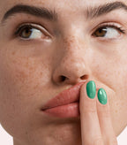 Close-up of a woman with Pink Gellac 271 Palmbeach Green manicured nails near her face.