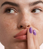 Close-up of a woman with Pink Gellac 273 Key Largo Purple manicured nails near her face.