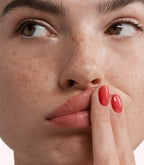 Close-up of a woman with Pink Gellac 281 Regal Red manicured nails near her face.