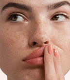 Close-up of a woman with Pink Gellac 286 Serenity Orange manicured nails near her face.