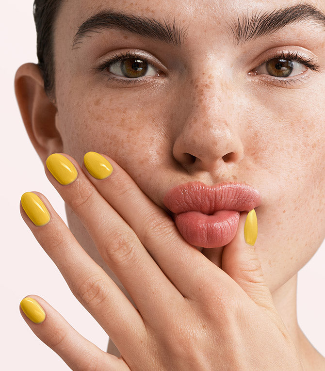Close-up of a woman with Pink Gellac 289 Breeze Yellow manicured nails near her face.