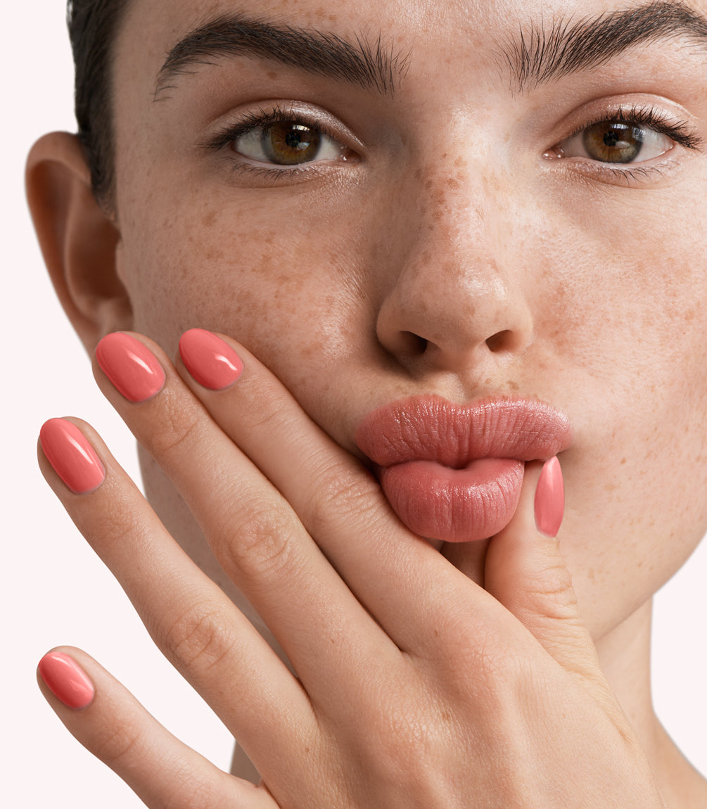 Close-up of a woman with Pink Gellac 290 Sunblaze Orange manicured nails near her face.