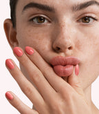 Close-up of a woman with Pink Gellac 290 Sunblaze Orange manicured nails near her face.