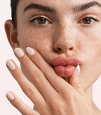 Close-up of a woman with Pink Gellac 294 Bridal Beige manicured nails near her face.