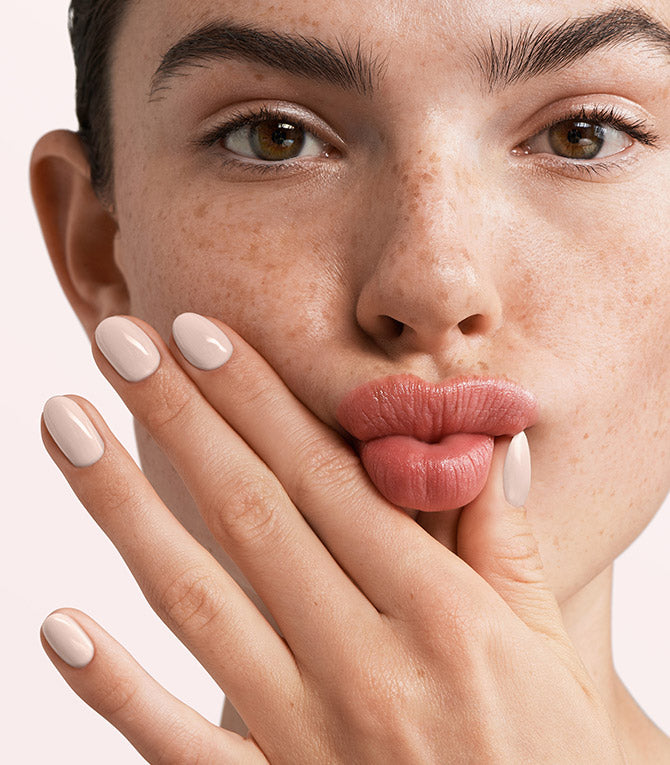 Close-up of a woman with Pink Gellac 294 Bridal Beige manicured nails near her face.