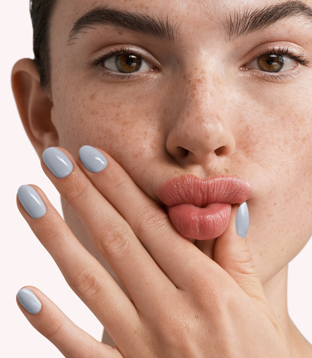 Close-up of a woman with Pink Gellac 295 Sky Grey manicured nails near her face.