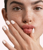 Close-up of a woman with Pink Gellac 296 Laced Cream manicured nails near her face.