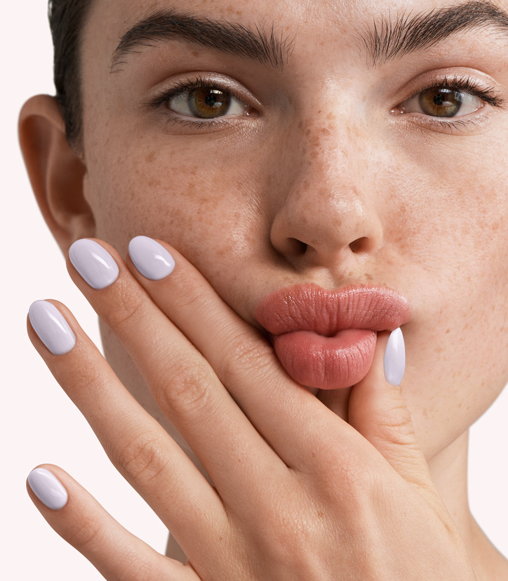 Close-up of a woman with Pink Gellac 297 Lavender Grey manicured nails near her face.