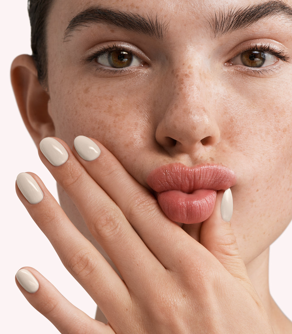 Close-up of a woman with Pink Gellac 298 Porcelain Beige manicured nails near her face.