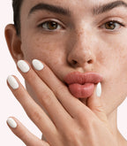 Close-up of a woman with Pink Gellac 299 Coco White manicured nails near her face.