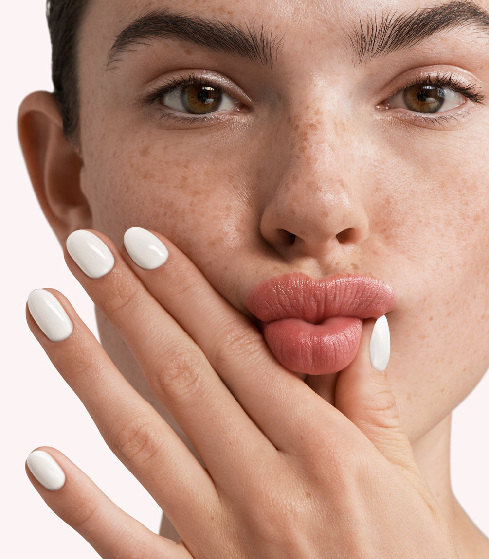 Close-up of a woman with Pink Gellac 299 Coco White manicured nails near her face.