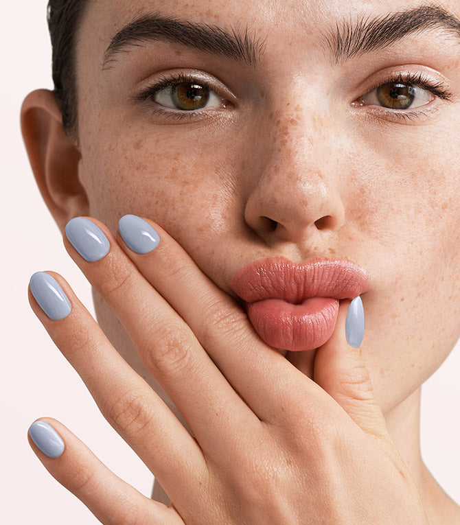Close-up of a woman with Pink Gellac 300 Light Blue manicured nails near her face.