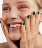 Close-up of a woman with Pink Gellac 303 Mermaid Green manicured nails near her face.