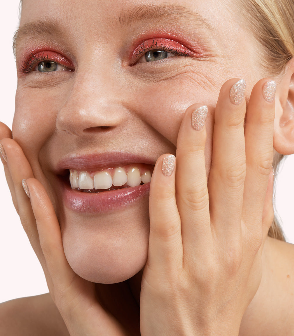 Close-up of a woman with Pink Gellac 304 Radiant White manicured nails near her face.