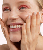 Close-up of a woman with Pink Gellac 304 Radiant White manicured nails near her face.