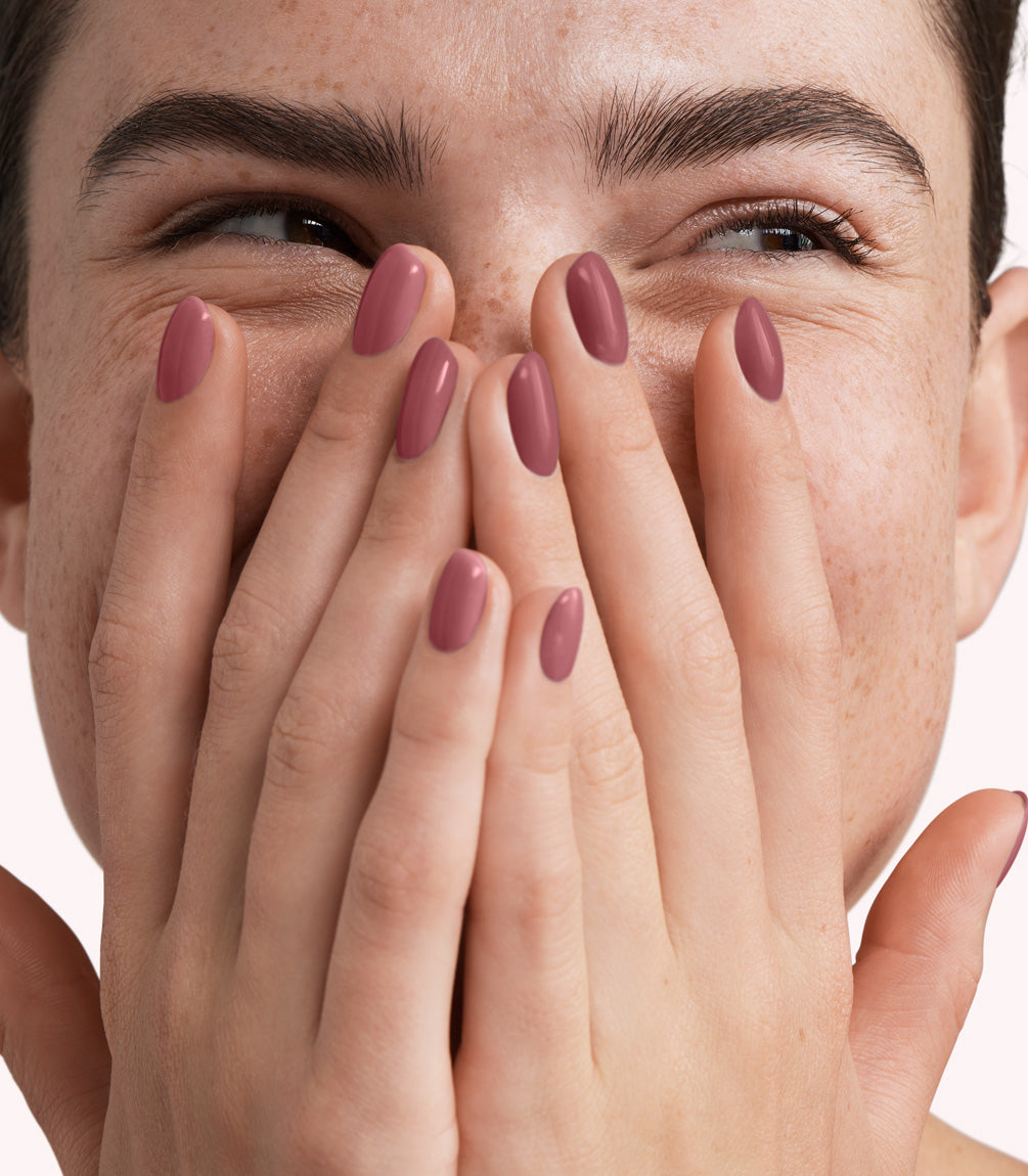 Close-up of a woman with Pink Gellac 306 Blissed Mauve manicured nails near her face.