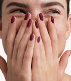 Close-up of a woman with Pink Gellac 307 Maroon Purple manicured nails near her face.
