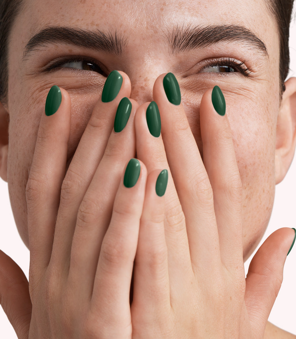 Close-up of a woman with Pink Gellac 309 Graceful Green manicured nails near her face.