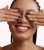 Close-up of a woman with Pink Gellac 313 Epic Purple manicured nails near her face.