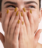 Close-up of a woman with Pink Gellac 315 Camel Gold manicured nails near her face.