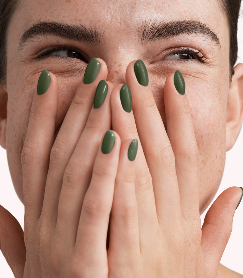Close-up of a woman with Pink Gellac 316 Jungle Green manicured nails near her face.