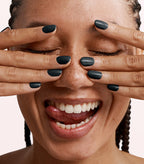 Close-up of a woman with Pink Gellac 317 Star Sky Black manicured nails near her face.
