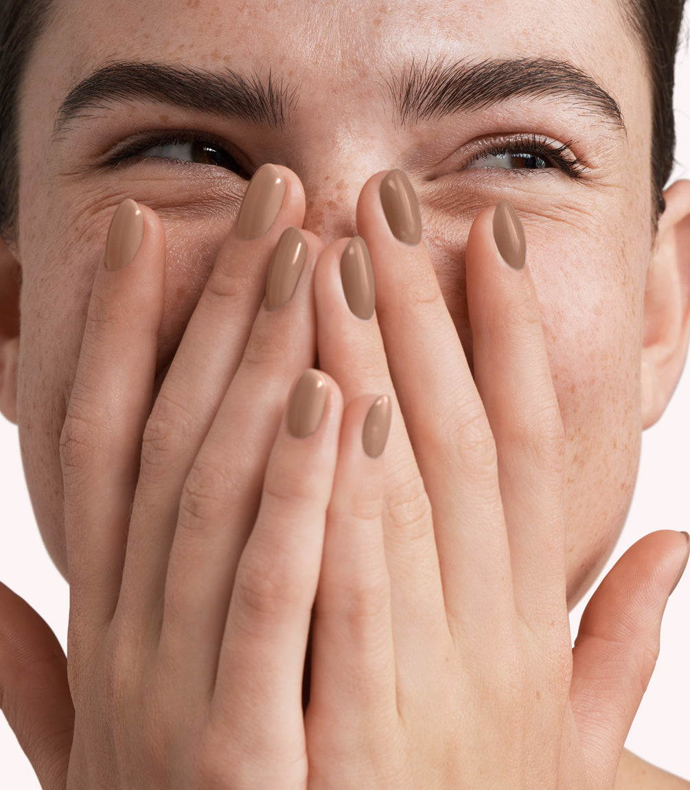 Close-up of a woman with Pink Gellac 318 Savanna Beige manicured nails near her face.