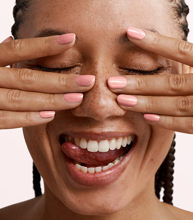 Close-up of a woman with Pink Gellac 322 Sparkle Peach manicured nails near her face.