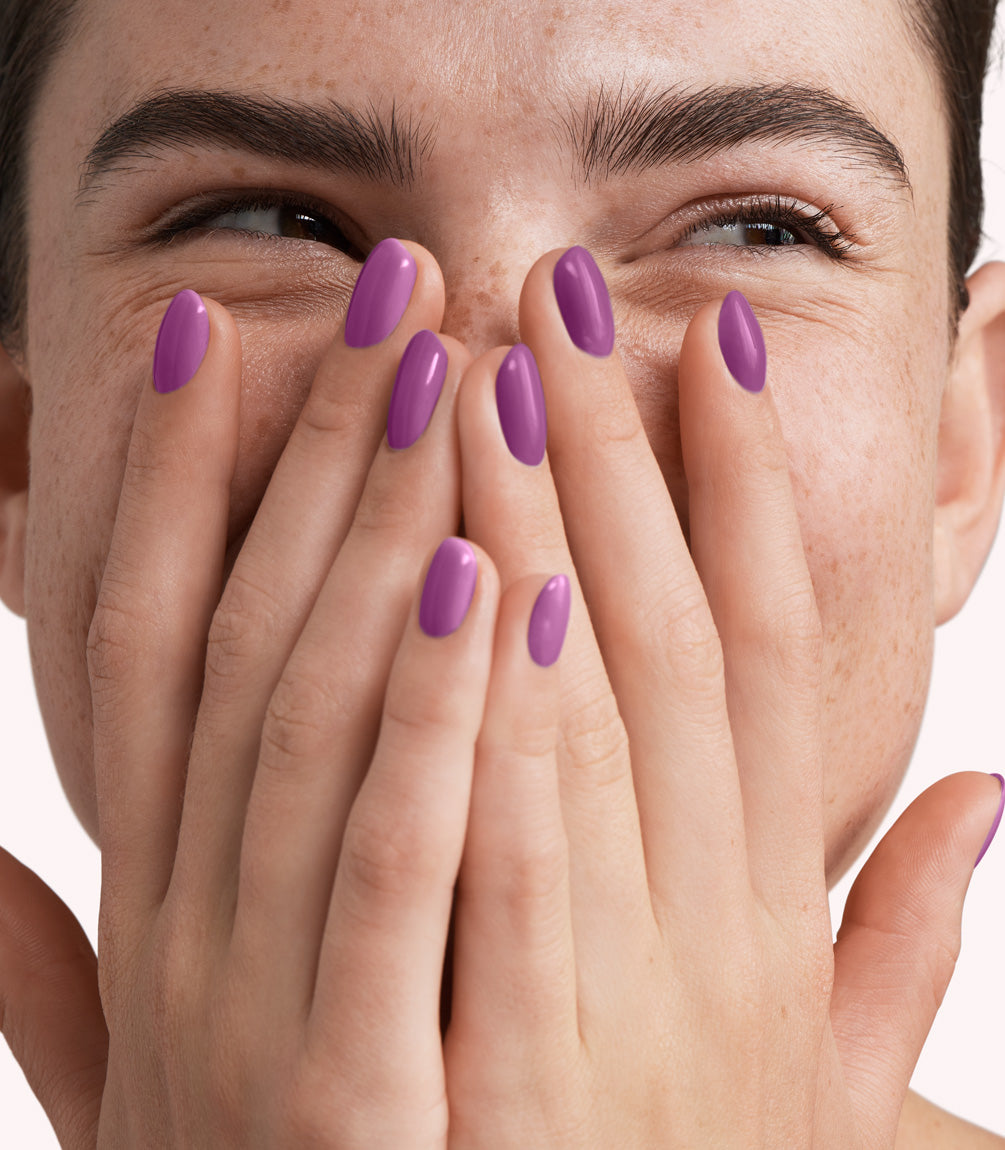 Close-up of a woman with Pink Gellac 328 Iris Purple manicured nails near her face.
