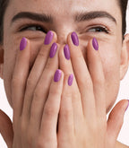 Close-up of a woman with Pink Gellac 328 Iris Purple manicured nails near her face.