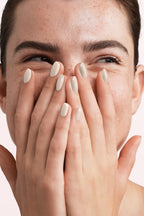 Close-up of a woman with Pink Gellac 329 Vanilla Cream manicured nails near her face.