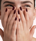 Close-up of a woman with Pink Gellac 332 Sangria Red manicured nails near her face.