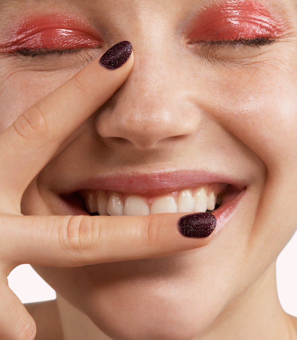 Close-up of a woman with Pink Gellac 333 Oriental Spice manicured nails near her face.